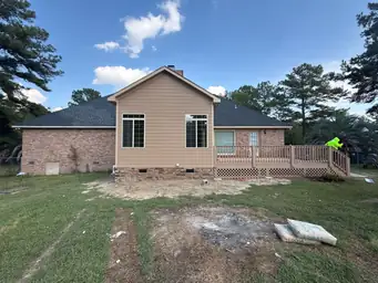 Rear exterior of home addition with tan fiber cement siding and large windows beside original brick facade after deck staining — Marietta, GA