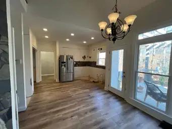 Open concept kitchen and dining area after new flooring — LVP hardwood installed, stone accent wall, sliding glass door to deck — Powder Springs, GA