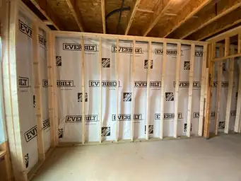 Basement framing with Everbilt vapor barrier installed across full stud wall, OSB ceiling joists visible above — Metro Atlanta, GA