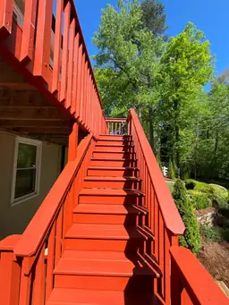 Newly installed pressure-treated wood stair treads and balusters with red stain applied after deck board installation — Marietta, GA