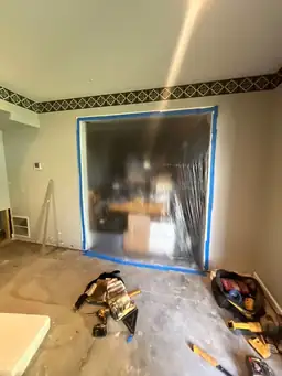 Room under renovation with plastic sheeting over an opening and construction tools on the floor — serving Dallas, GA.