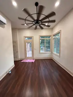 Finished sunroom addition interior with dark hardwood flooring, ceiling fan, and door to deck after roof installation — Marietta, GA