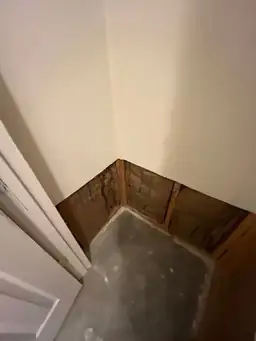 Exposed wall insulation and concrete floor in a room corner, with drywall removed — serving Dallas, GA.