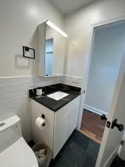 Finished bathroom remodel showing full white subway tile tub surround, matte black shower fixtures, and dark slate floor — Marietta, GA