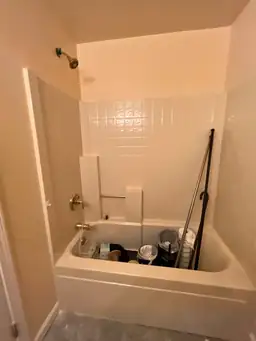 Bathroom during renovation showing a bathtub filled with cleaning supplies and tools. Tiled walls and a showerhead are visible — serving Dallas, GA.