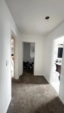Repaired interior hallway with fresh drywall, attic access panel, and adjacent bathroom after storm damage restoration — Acworth, GA