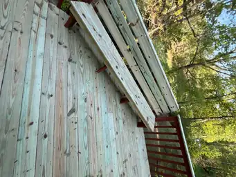 Close-up of weathered gray and green pressure-treated fascia boards before deck staining on elevated exterior — Marietta, GA