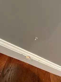 Baseboard with chipped paint and wall dent in a home interior — serving Dallas, GA.