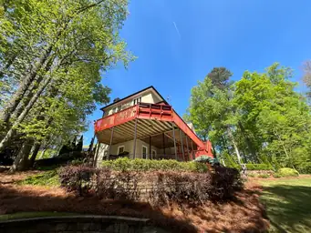 Wide-angle view of elevated red-painted wood deck and lower covered patio before board replacement begins — Marietta, GA