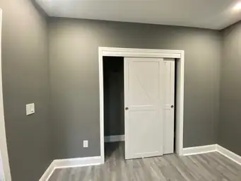 Finished basement bedroom with charcoal gray walls, white sliding barn-style closet doors, and gray LVP flooring — Metro Atlanta, GA