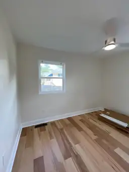 Bedroom flooring installation during home remodel with light hickory hardwood planks being laid and baseboard trim staged — Marietta, GA