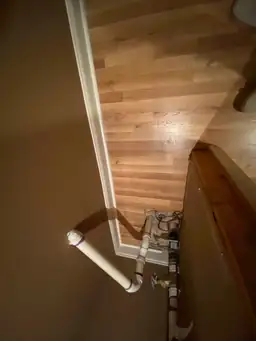 Overhead view of restored hardwood flooring near PVC drain pipe and utility connections at doorway after water damage repair — Marietta, GA