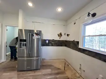 Kitchen demo in progress — cabinets removed, stone backsplash being demolished, contractor working on gut renovation — Powder Springs, GA