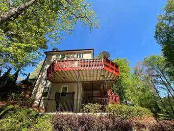 Elevated two-story deck with red-painted wood boards and balusters before deck repair viewed from backyard — Marietta, GA