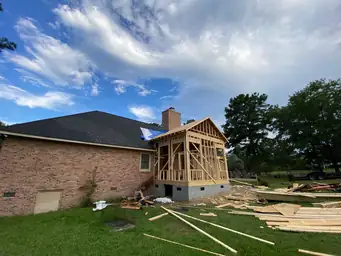 Wide exterior view of sunroom addition open wood gable framing and roof structure during deck board installation phase — Marietta, GA