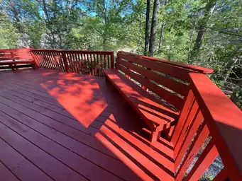 Freshly stained red deck surface with matching built-in benches and railing after deck board replacement — Marietta, GA