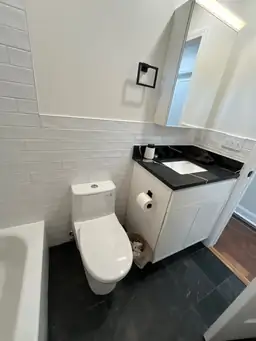 Completed bathroom vanity with white shaker cabinet, dark quartz countertop, white subway tile backsplash, and recessed mirror — Marietta, GA