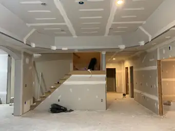Basement drywall installation with stair stringer framed and recessed tray platform mudded and taped — Atlanta, GA