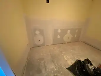 New gray drywall sheets with joint compound applied low on basement wall, concrete slab floor cleared during restoration — Marietta, GA