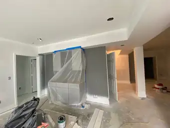 Basement painting phase with primed drywall walls, cabinetry shrink-wrapped for protection, doors and columns installed — Metro Atlanta, GA