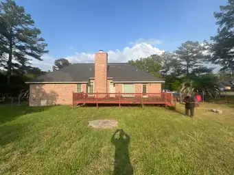 Final showcase of brick home rear exterior with completed tan siding addition, composite deck, and railing installed — Marietta, GA
