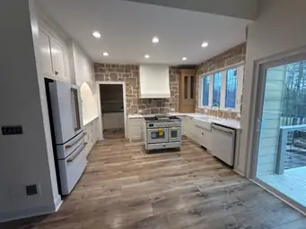 Kitchen renovation completed — white shaker cabinets, stone accent wall, professional dual-oven range, farmhouse sink, new hardwood floors — Powder Springs, GA