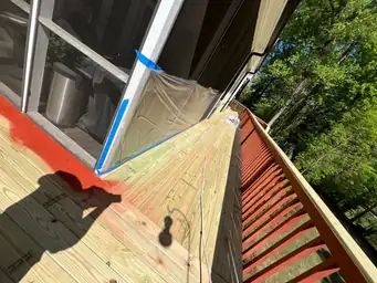 Pressure-treated green-tinted new wood deck boards mid-installation with blue painter tape protecting door frame — Marietta, GA