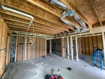 Basement mechanical rough-in with flexible HVAC ductwork, PEX plumbing runs, and electrical wiring across open ceiling — Metro Atlanta, GA