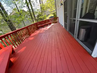 Freshly stained red deck boards with glossy finish along screened porch wall after stain application complete — Marietta, GA