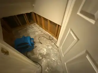 A room with exposed wooden studs in the wall, concrete floor, and a blue air mover, indicating water mitigation work — serving Dallas, GA.