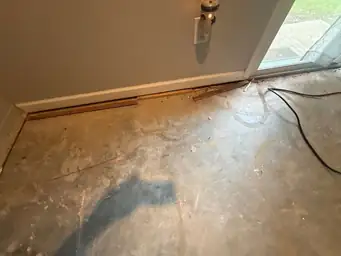 Room with cement floor and wooden trim during construction phase. Near wall with electrical outlet and glass door — serving Dallas, GA.
