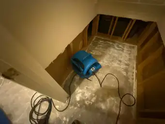 Blue air mover in a room with removed drywall and exposed studs during water mitigation — serving Dallas, GA.