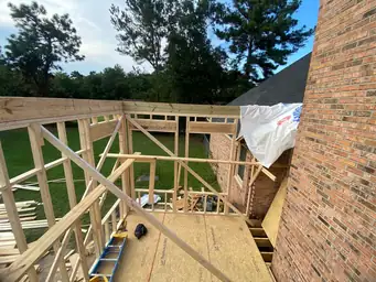 Rear exterior of home addition with house wrap applied and pressure-treated deck framing and railing structure in progress — Marietta, GA