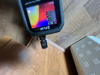 FLIR MR176 moisture meter scanning hardwood floor baseboard during water damage assessment — Marietta, GA