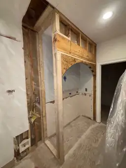 Wall framing for new arched pass-through opening during kitchen renovation — structural framing and drywall in progress — Powder Springs, GA