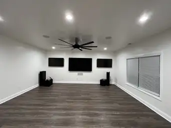 Home theater with triple wall-mounted TVs, surround sound speakers, dark wood plank ceiling, and polished floor — Metro Atlanta, GA