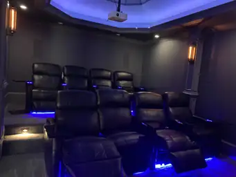 Finished basement home theater with tiered leather recliners, blue LED accent lighting, and large projector screen — Atlanta, GA
