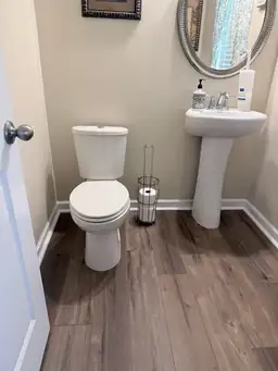 Bathroom with new toilet, pedestal sink, and wood-look flooring after remodeling — serving Dallas, GA.