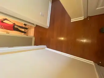 Completed hardwood flooring in a hallway with a person working in the background — serving Dallas, GA.