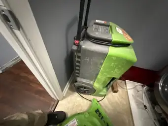 Green air movers deployed on dark hardwood floor during water intrusion dry-out near French doors — Smyrna, GA