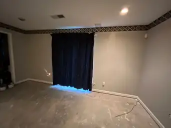 Room undergoing construction with unfinished floor and curtains over window — serving Dallas, GA.