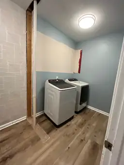 Laundry room renovation complete — new washer and dryer, LVP hardwood floors, blue painted walls, painted brick accent wall — Powder Springs, GA