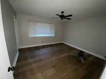 Bedroom after water damage restoration with new dark hardwood floors, fresh grey walls, and black ceiling fan — Kennesaw, GA