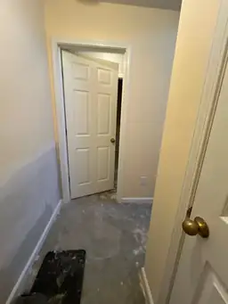 Hallway under renovation with partially painted walls and unfinished concrete floor — serving Dallas, GA.