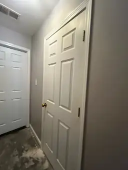 Hallway with freshly painted doors and unfinished floor, indicating construction work — serving Dallas, GA.