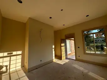 Sunroom addition interior during framing with recessed lights roughed in, yellow-tinted drywall, and bare concrete subfloor — Marietta, GA
