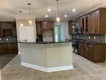 Kitchen restoration with dark wood cabinets, stone-tile backsplash, wine rack built-in, and pendant lighting — Atlanta, GA