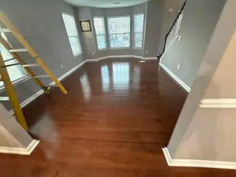 Living room after water damage repair with refinished cherry hardwood floors, grey walls, and large bay windows — Smyrna, GA