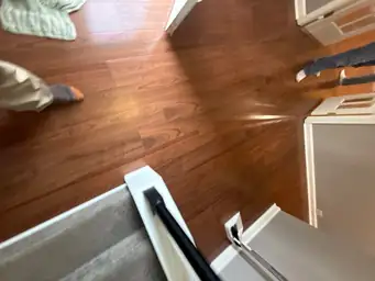 Worker inspecting cherry hardwood floors near staircase landing during water damage restoration walkthrough — Smyrna, GA
