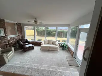 Sunroom before storm damage restoration showing furnished living space with carpet, brick walls, and intact ceiling — Marietta, GA